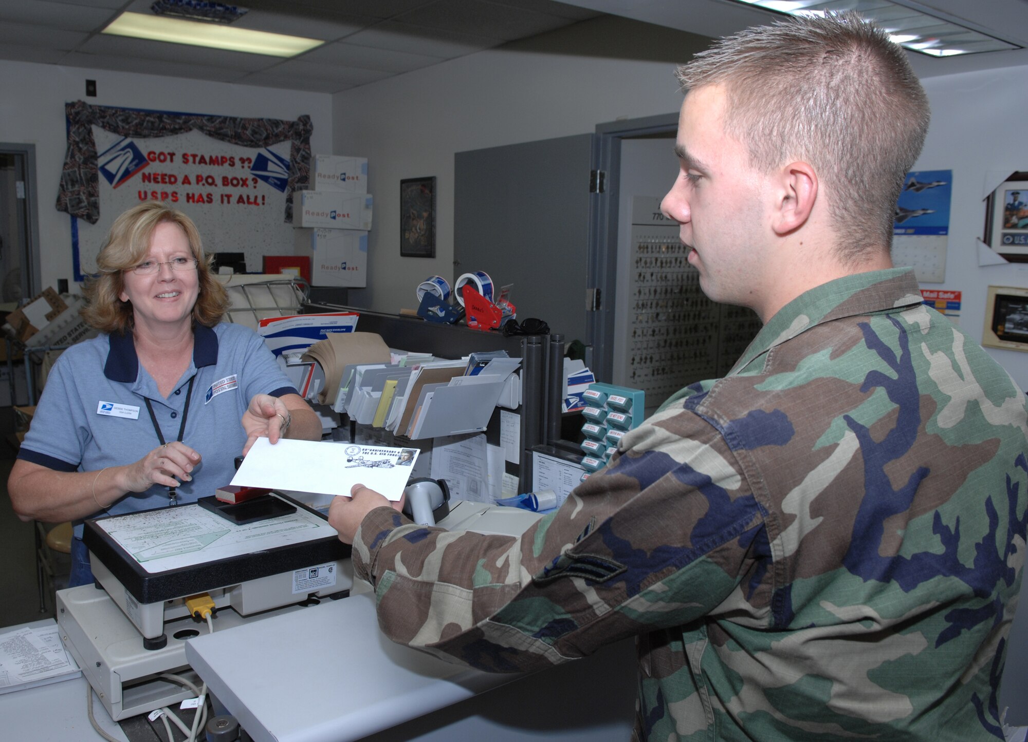 WHITEMAN AIR FORCE BASE, Mo. -- Debbie Thompson, Whiteman Air Force Base Post Office, hands Airman 1st Class Cory Todd, 509th Communications Squadron, a letter with a commemorative postmark and Jimmy Stewart stamp to mark the 60th Anniversary of the Air Force Sept. 18 at the post office. (U.S. Air Force photo by Airman 1st Class Stephen Linch) 