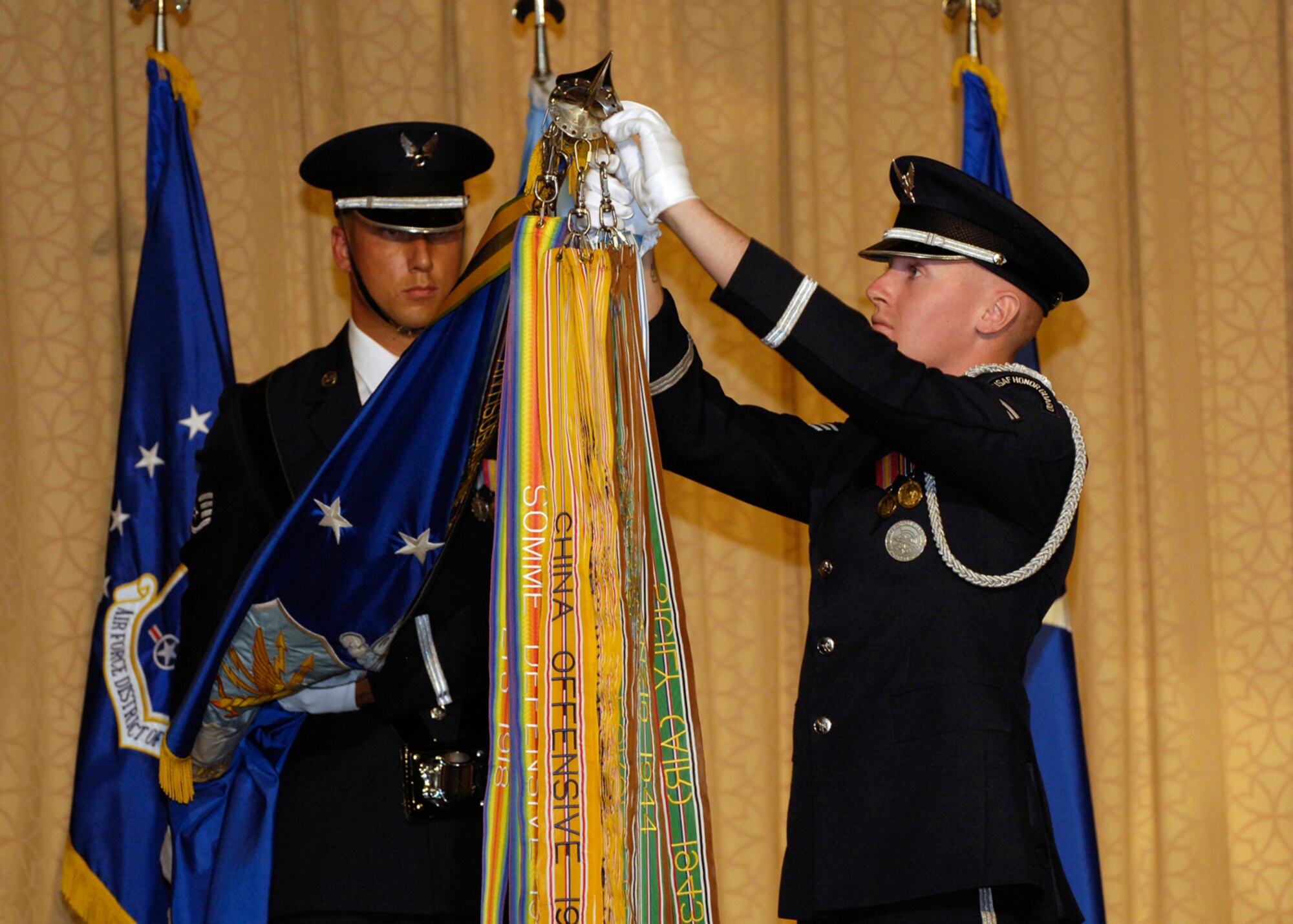 Air Force honor Guard member Staff Sgt. Michael Rowson holds the guidon with the Air Force flag as Senior Airman Jonathan Pinkam clips on the last of 13 streamers, showing the entire audience the flag with full honors. The history of the Air Frorce Flag and each streamer was discussed during the ball Sept. 15.
