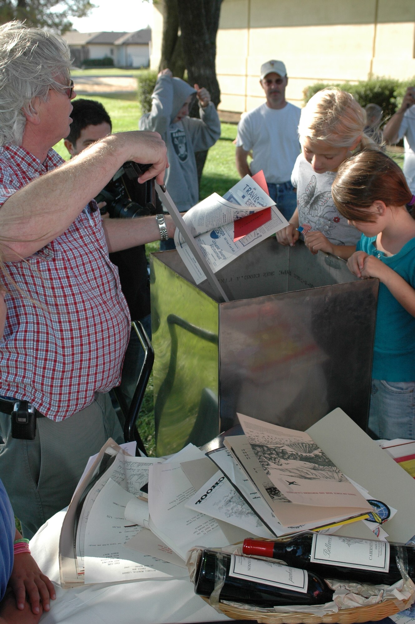 Anthony Gonzales, senior library technician, removes the contents of a 25-year-old time capsule during the 60th Air Force Birthday Celebration at the Mitchell Memorial Library Sept. 18. The time capsule contained various items donated from agencies around the base during the year of 1982. The contents included squadron patches, base/school newspapers, various records and tapes including a proclamation from Travis’ leadership, and two 1979 Napa wine bottles. (U.S. Air Force photo/Staff Sgt. Matthew McGovern) 