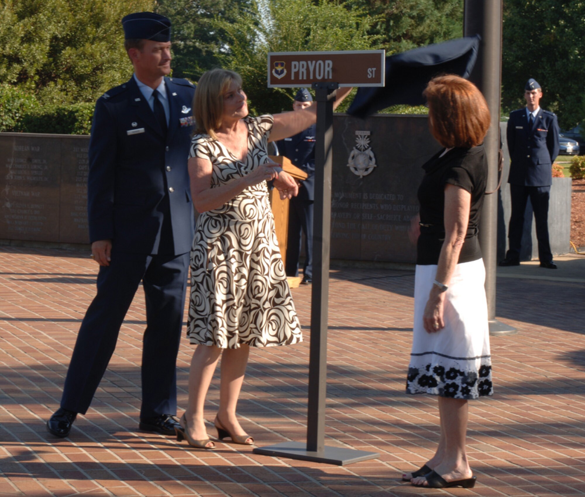 Celia Pryor Plenge and Elaine Pryor Davis, daughters of former WW II POW Col Roger Pryor, unveil a new street sign during the POW/MIA retreat ceremony Wednesday as Colonel Dave Gerber, 14th Flying Training Wing commander looks on.  Pryor Street will replace A street on Columbus AFB, Miss.  (U.S. Air Force photo by Airman 1st Class Danielle Powell)
