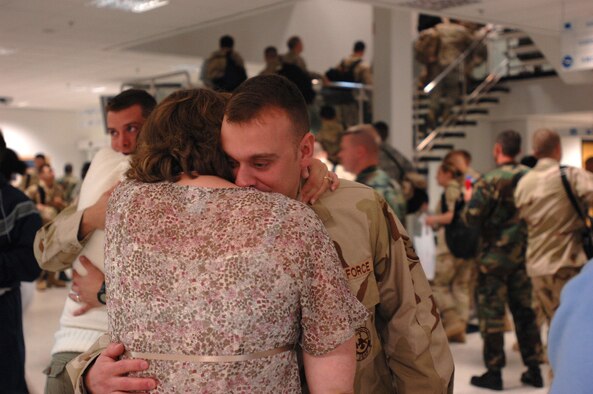 As other RAF Mildenhall Airmen form a line for boarding an Air Mobility Command aircraft destined for various deployment locations, Staff Sgt. Jason Procknal, 100th Civil Engineer Squadron firefighter, embraces his pregnant wife Amanda, who is a 100th Services Squadron staff sergeant. Sergeant Procknal has two sons staying with mom while he is downrange. (U.S. Air Force photo by Tech. Sgt. Tracy L. DeMarco)
