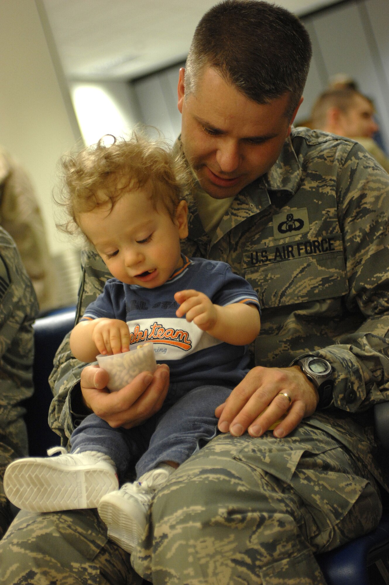 While waiting for his flight, Master Sgt. Michael Lang, a 100th Operations Support Squadron Airman, holds his 16-month-old son Nathaniel at the RAF Mildenhall passenger terminal, Sept. 14, 2007. This will be Sergeant Lang's third deployment but only his first as a father. The plane was an hour late arriving that morning giving Sergeant Lang time to help Nathaniel eat his cereal.  (U.S. Air Force photo by Tech. Sgt. Tracy L. DeMarco)
