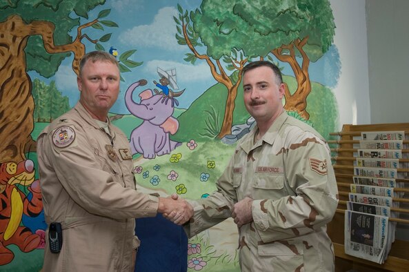 SOUTHWEST ASIA -- Col. Robert Swisher, 386th Air Expeditionary Wing Commander, presents Staff Sgt. Matthew Cremeans, 386th Expeditionary Mainteance Squadron, consolidated tool crib NCO in charge, with a wing coin for painting the mural at the Learning Resource Center on Sept 15.  Staff Sgt. Cremeans is deployed from Ramstein Air Base, Germany.  (U.S. Air Force photo by Staff Sgt. Tia Schroeder)