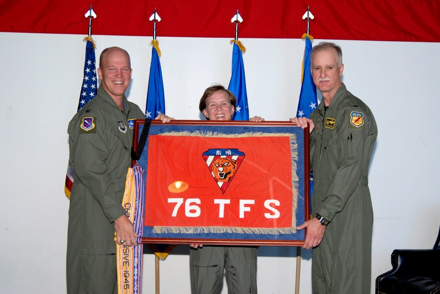 Col. Jay Raymond (left), 21st Space Wing commander at Peterson Air Force Base, Colo., and Lt. Col. Jennifer Moore, 76th Space Control Squadron commander at Peterson, pass the squadron's share of the Flying Tigers heritage to Col. Steve Arthur, 442nd Fighter Wing commander at Whiteman AFB, Mo. Reservists from the 442nd FW are forming the new 76th Fighter Squadron that will assume the heritage, reuniting the three pieces of the Flying Tigers legacy held by the 74th, 75th and 76th squadrons, under the 23rd Fighter Wing for the first time since World War II. (U.S. Air Force photo/Roberta McDonald)