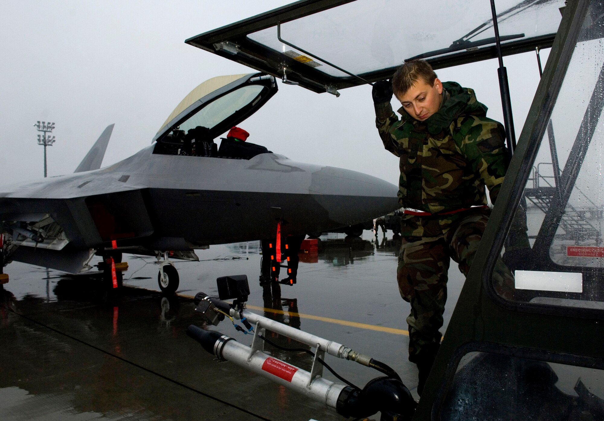 Airman 1st Class Alexander Buck climbs into a de-icer Sept. 19 at Elmendorf Air Force Base, Alaska, prior to practicing de-icing techniques on an F-22 Raptor.  The de-icing test will help officials gather technical data on how cold weather effects the maintenance crew's capabilities while working with this aircraft during the winter. The onset of light dustings of snow on the surrounding mountain ranges is a sign the Alaskan winter is just around the corner.  Airman Buck is assigned to the 3rd Aircraft Maintenance Squadron.  (U.S. Air Force photo/Senior Airman Garrett Hothan)