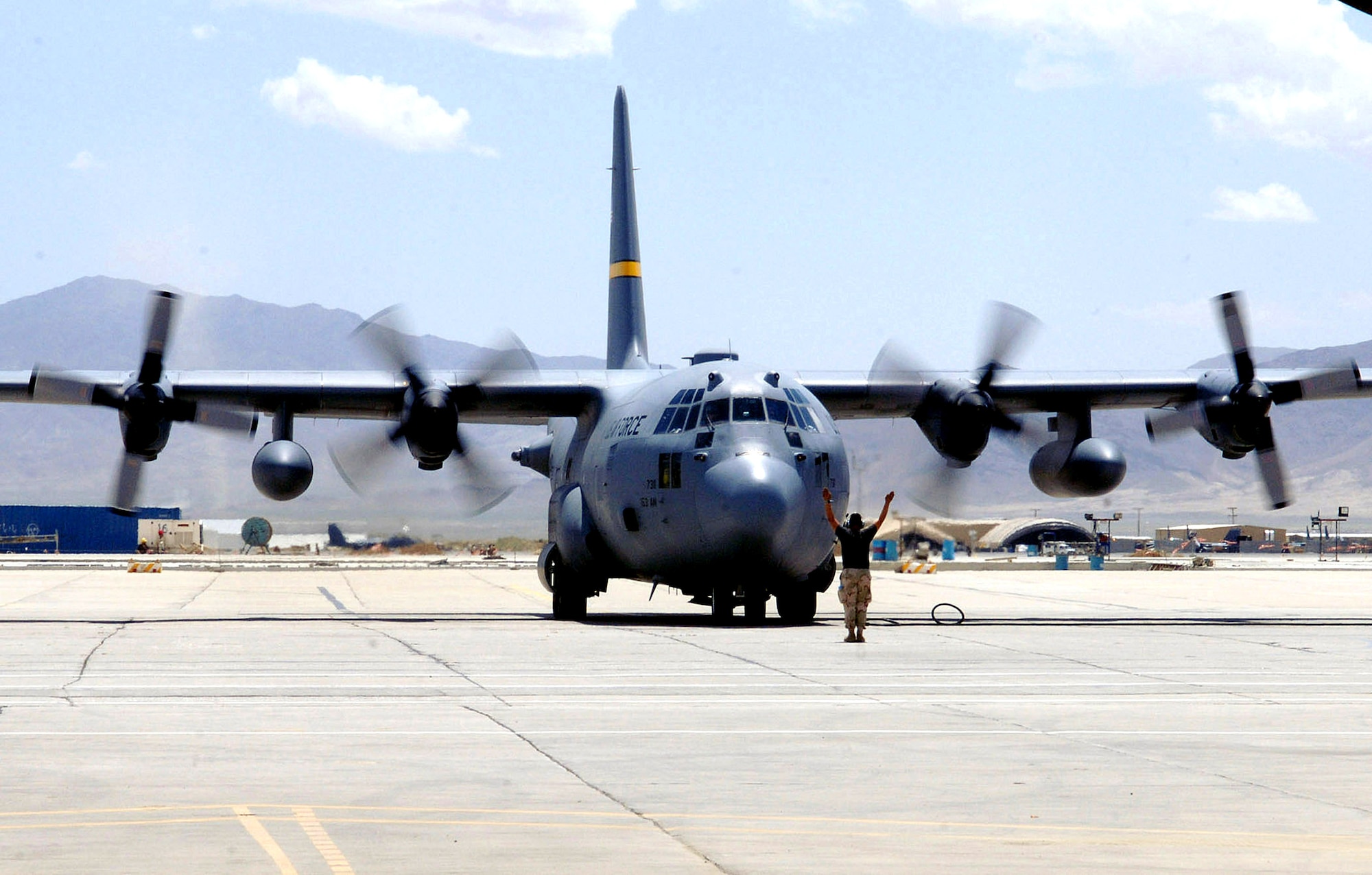 A C-130 Hercules crew chief from the 455th Expeditionary Maintenance Group marshals a Hercules to its parking spot on the flightline at Bagram Airfield, Afghanistan.  C-130s provide intra-theater airlift support to sustain operations throughout Southwest Asia.  (U.S. Air Force photo/Staff Sgt. Craig Seals)