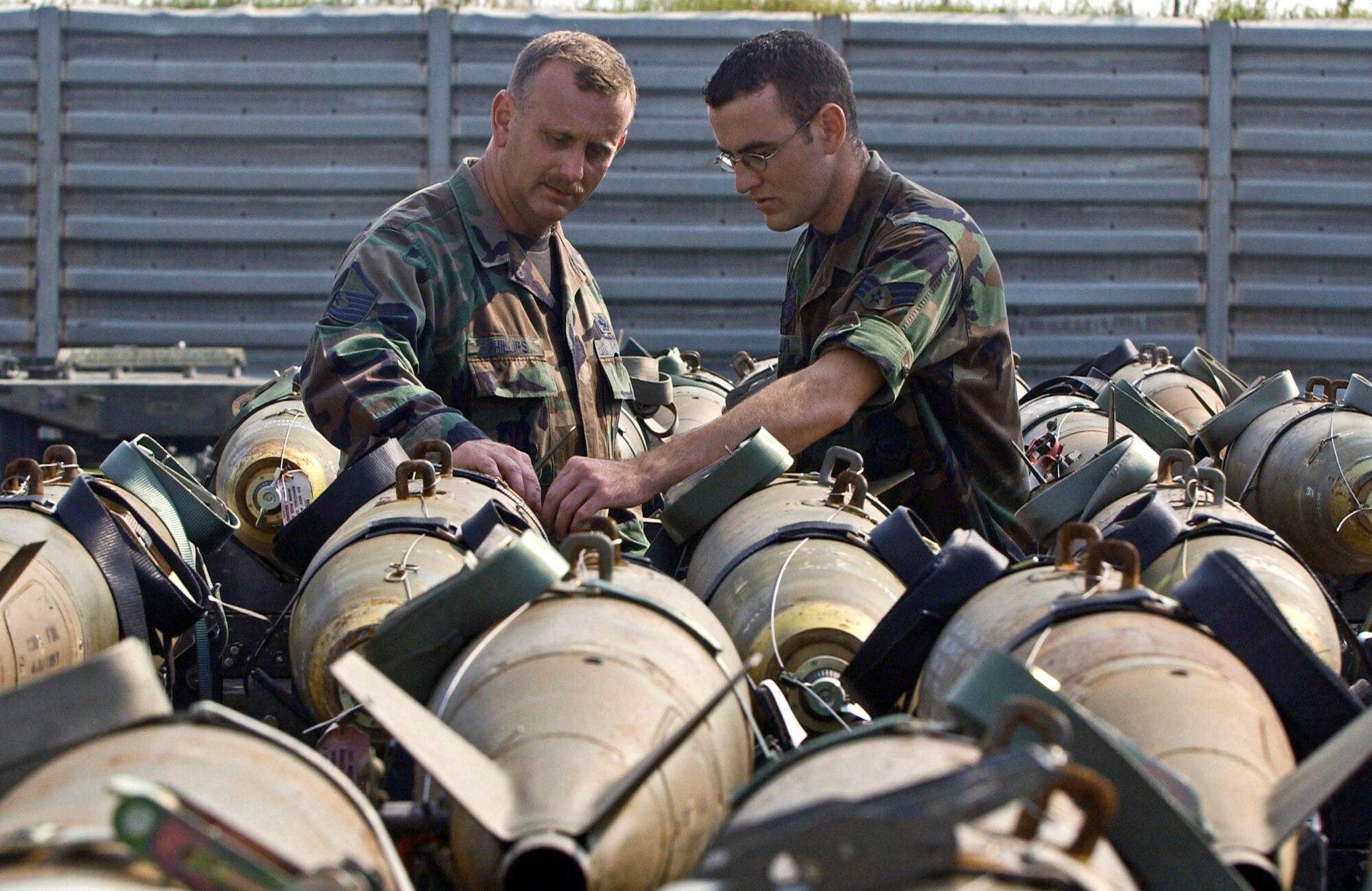 Master Sgt. Torre Phillips (left) inspects an MK-82 bomb Sept. 13 at Kunsan Air Base, South Korea, with his son, Senior Airman David Phillips.  Sergeant Phillips is deployed to Kunsan for a four-month rotation while his son completes his one-year remote tour here. (U.S. Air Force photo/Senior Airman Steven Doty)           