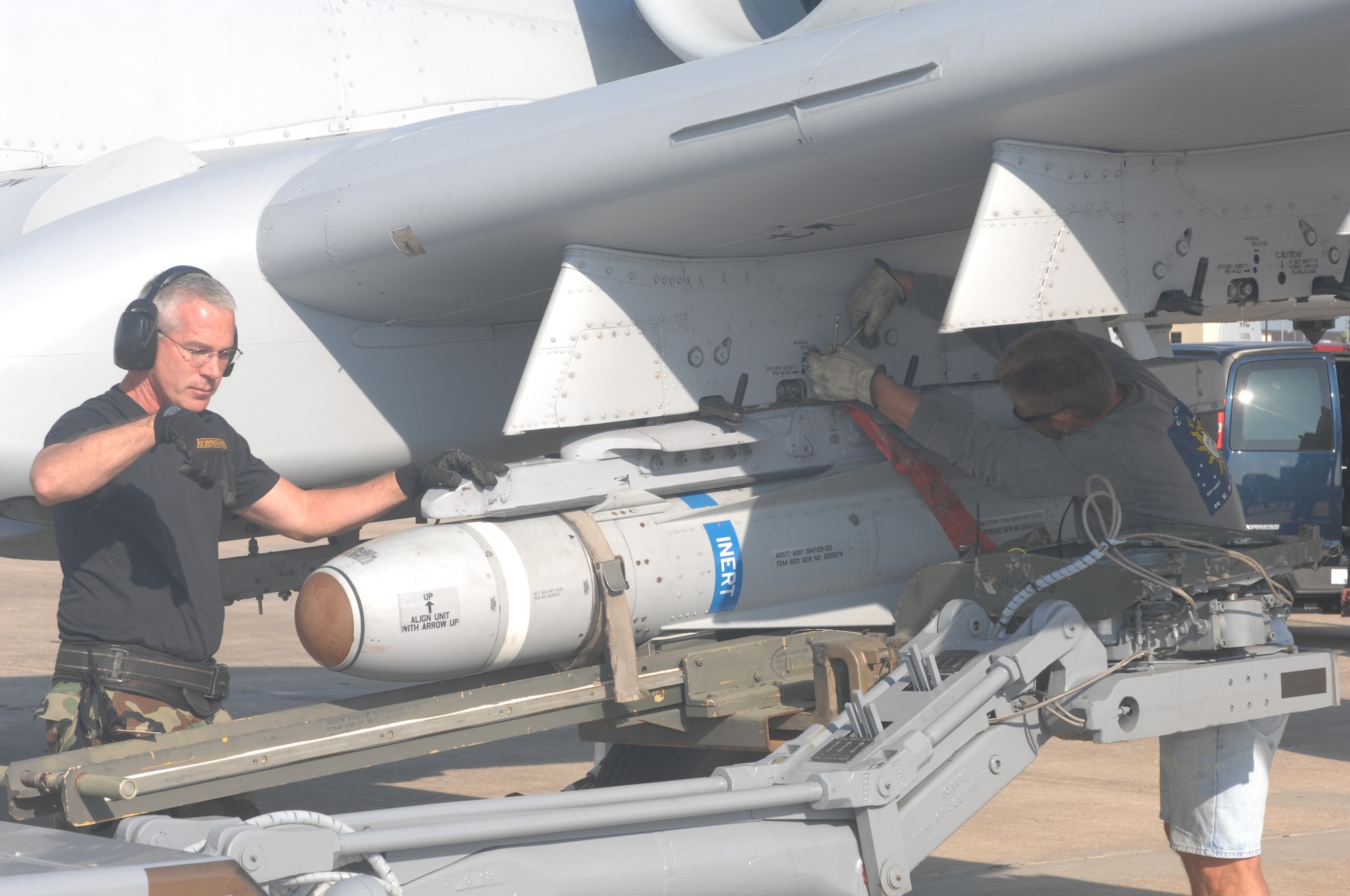 WHITEMAN AIR FORCE BASE, Mo. -- Master Sgt. Edward Coyle, 442nd Aircraft Maintenance Squadron, (left) gives commands through hand signals to the driver of a jammer while Jim Smitka, 442nd AMXS, locks an AGM-65 Maverick  to a weapons pylon station Sept. 17. (U.S. Air Force photo/Tech. Sgt. Samuel A. Park)

