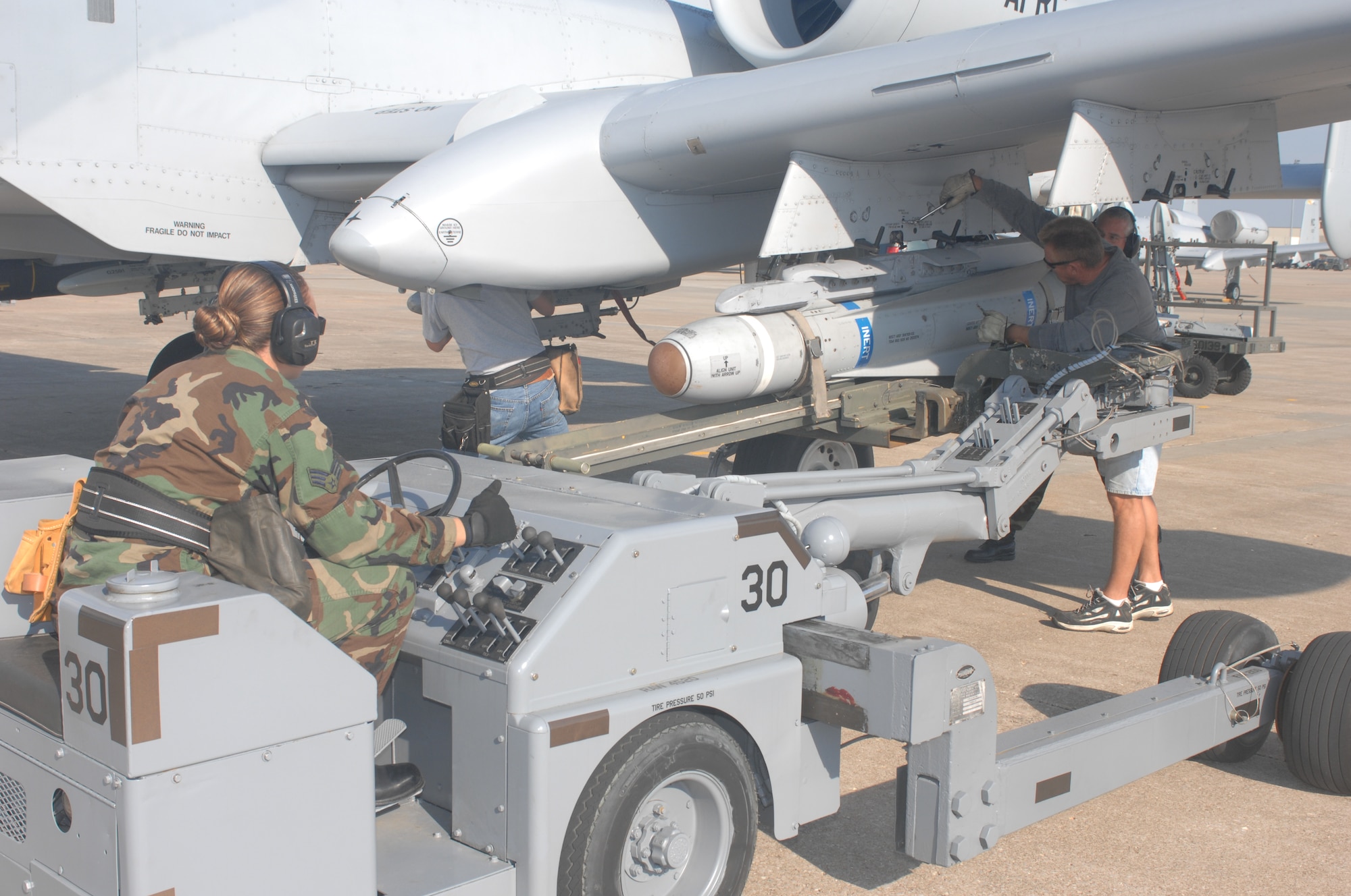 WHITEMAN AIR FORCE BASE, Mo. -- Senior Airman Jennifer Laspino, 442nd Aircraft Maintenance Squadron, adjusts the position of an AGM-65 Maverick on a jammer to line up with an A-10 weapons pylon station. Master Sgt. Edward Coyle and Jim Smitka, both from the 442d AMXS, prepare to lock the missile to the station Sept. 17. Although the missiles are inert, pilots from the 442nd Fighter Wing fly training sorties with the missiles attached to practice targeting techniques. (U.S. Air Force photo/Tech. Sgt. Samuel A. Park) 
