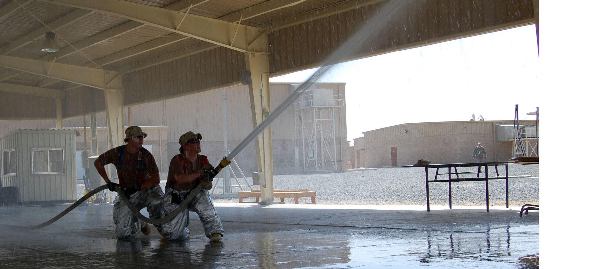 Staff Sgt. Thomas Nickle and Senior Airman Bradley Schneider, 386th Expeditionary Civil Engineer Squadron fire protection firemen, Practice their sweep tecnique for putting out ceiling fires Sept.  21 in the Rock's pavillion. Fighting fires is a dangerious job, so fire must train regularly to keep current. 