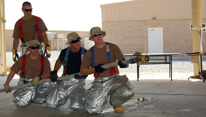 Left: Tech. Sgt. Erik Lahoda, Staff Sgt. Thomas Nickle, Master Sgt. Mike Wou and Senior Airman Bradley Schneider, 386th Expeditionary Civil Engineer Squadron fire protection firemen, train on how to put out a room fire Sept.  21 in the Rock's pavillion. By conducting annuel refresher courses, firemen here keep their skills sharp.