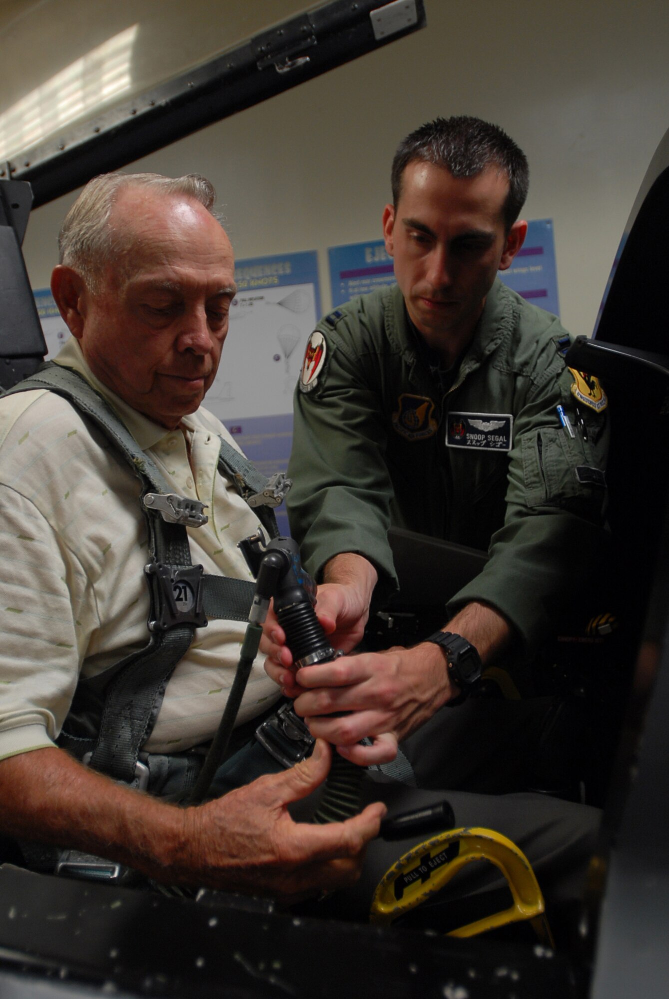 Capt. Ronen Segal shows how to attach the oxygen mask to Col. (ret.) and former Prisoner of War Jim Lamar in the emergency egress cockpit trainer during his egress training  at Kadnea Air Base, Japan, Sept. 20, 2007. Mr. Lamar was a POW during Vietnam and will be speaking at the base's POW/MIA ceremony Sept. 21.  After the ceremony, Mr. Lamar will receive an F-15C Eagle orientation flight. Captain Segal is a pilot with the 44th Fighter Squadron. (U.S. Air Force photo/Senior Airman Darnell T. Cannady)