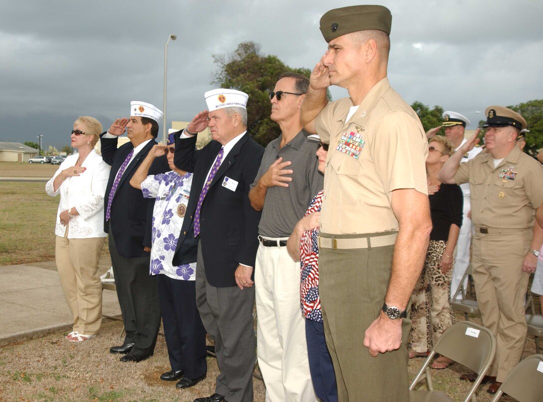 Colonel Mark A. Dungan, (right) commanding officer, Marine Corps Base Hawaii, salutes during morning colors with retired Col. Richard Esau (fourth from left). Esau met with Dungan to discuss veteranÕs programs offered through the Military Order of the Purple Heart Service Foundation.