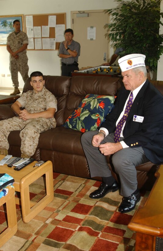 Corporal Ryan Irving, infantryman, 2nd Battalion, 3rd Marine Regiment, (front) listens to retired Col. Richard Esau speak about his combat experiences at the Wounded Warriors lounge. He spoke to the Marines about the foundationÕs programs, such as Combat Call Center where veterans work as phone support operators.