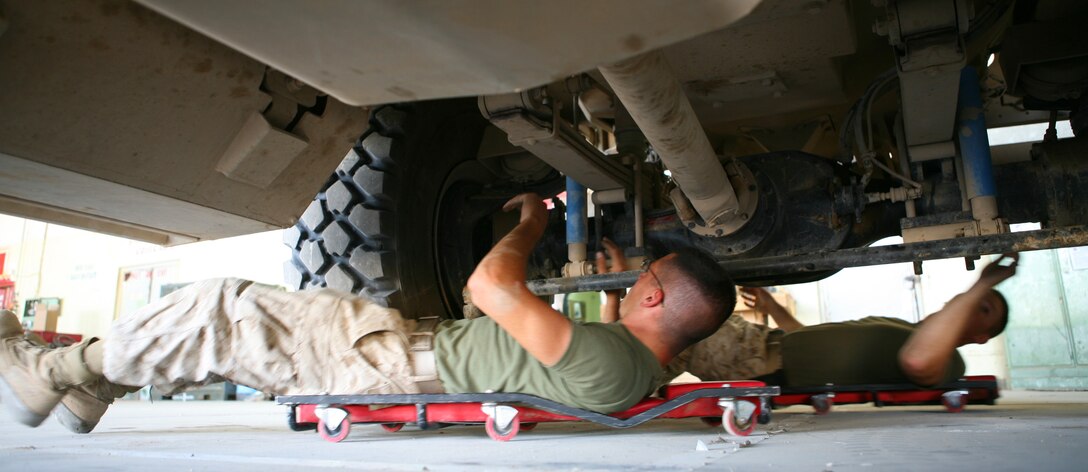 AL ASAD, Iraq- Task Force Military Police, 1st Battalion, 12th Marine Regiment, motor transportation Marines check the undercarriage of a Cougar model Mine Resistant Ambush Protected vehicle prior to sending it out on patrol, Sept. 22.  The mechanics check for any damaged parts and ensure all the proper parts are lubricated.