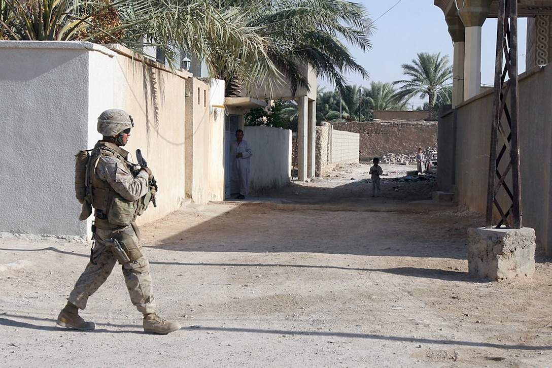 EXPEDITIONARY PATROL BASE - DULAB, Iraq, (Sept. 26, 2007) – A Marine with Weapons Company, 1st Battalion, 7th Marine Regiment, Regimental Combat Team 2, crosses an alleyway while on a security patrol as an Iraqi child and his father look on in the darkness. It is not unusual for the Marines in the battalion to spend the entire day, sunrise to sunset, on patrols. Official Marine Corps Photo By Cpl. Ryan C. Heiser.