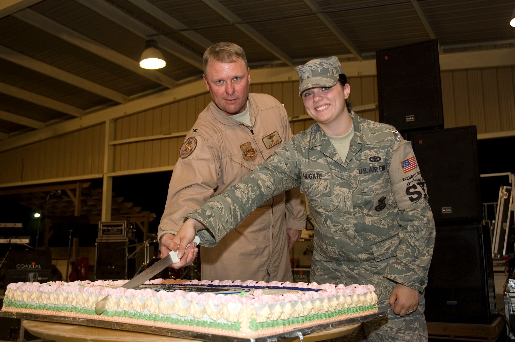Col. Robert Swisher, 386th Air Expeditionary Wing, commander, and Airman 1st Class Cassandra Hugate, 387th Security Forces Squadron member, cut the first slice of cake to kick of the week long Air Force's 60th birthday celebration on Sept. 17.  (U.S. Air Force photo by Staff Sgt. Tia Schroeder)

