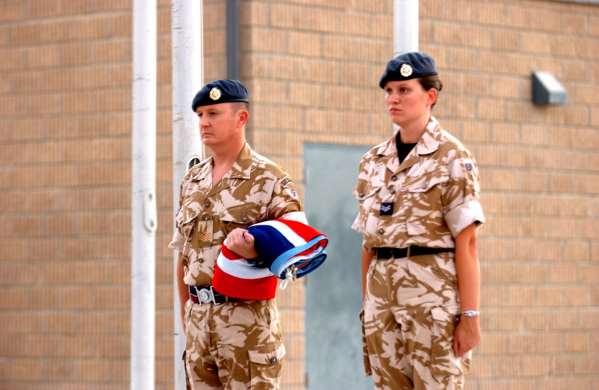 SOUTHWEST ASIA -- Flt Sgt. Tim Miles and Cpl. Jackie Chesters of the Royal Air Force stand at attention after lowering the ceremonial flag during a ceremony commemorating the Battle of Britian, Sept. 15. (U.S. Air Force photo/Master Sgt. Greg Kunkle)
