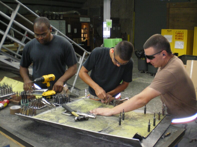 SOUTHWEST ASIA -- Staff Sgt. Jamel Robinson, Staff Sgt. Roberto Peralta and Senior Airman Justin Shepard, 379th Expeditionary Aircraft Maintenance Squadron, perform “reconstructive” surgery on a B-1 Bomber panel with misaligned fastener holes. Repair work such as this is normally performed at the depot level. (U.S. Air Force photo/Lt. Col. Scott Fike)