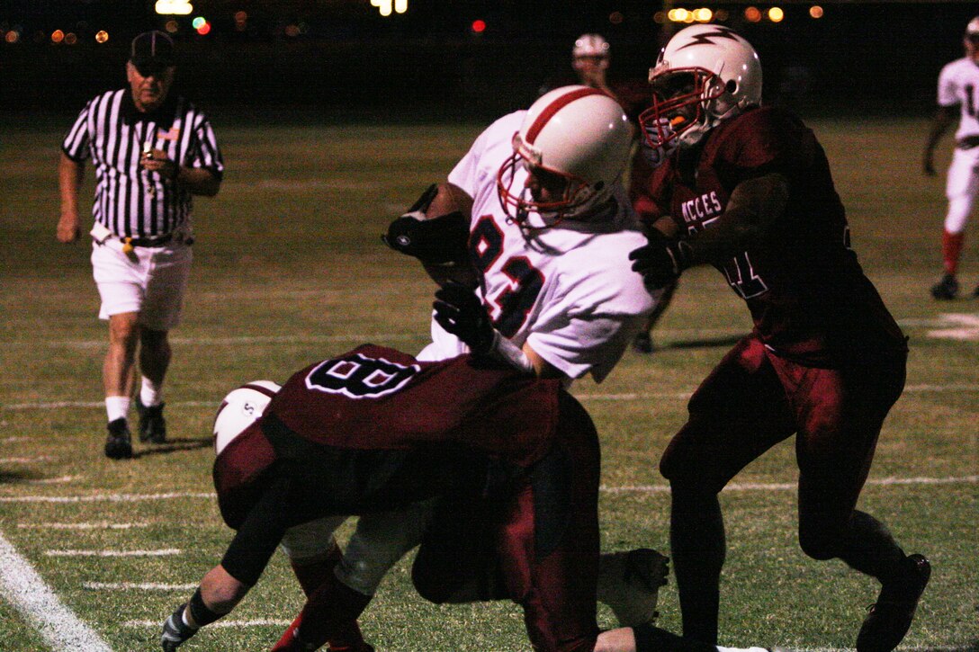 Victor Runsewe, Headquarters Battalion wide receiver, turns his reception into a first down by powering past two Marine Corps Communication-Electronics School defenders at Felix Field Sept. 24. Headquarters went on to win the game by a touchdown, 32-26.