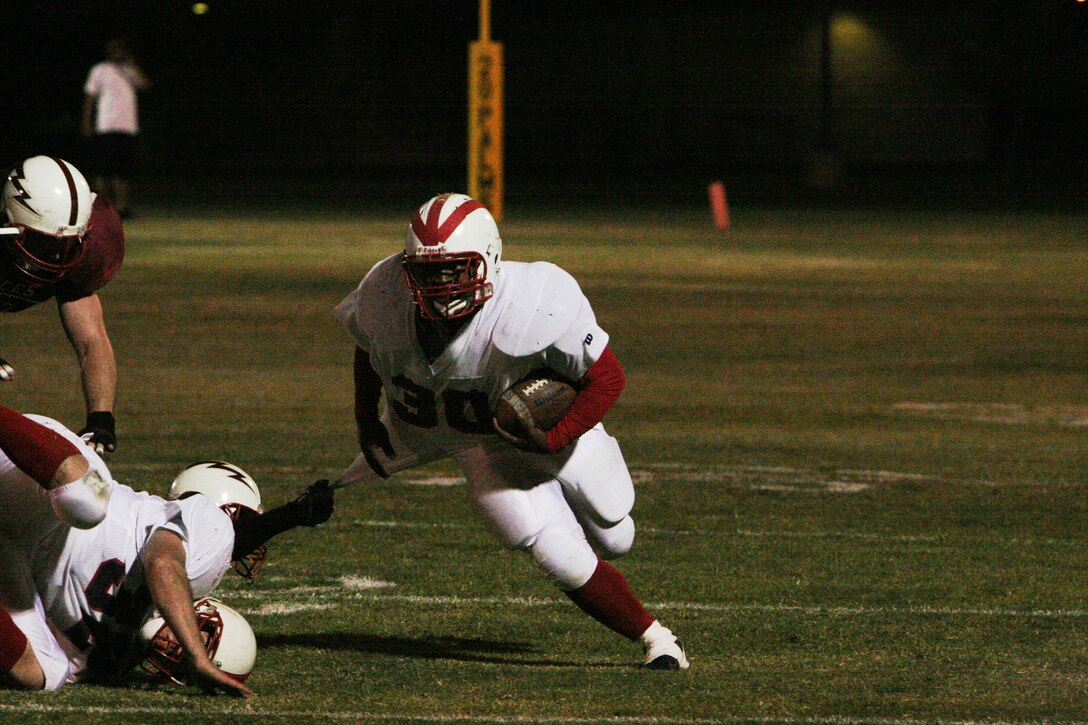 Willie Campbell, Headquarters Battalion running back, slides through the grip of the Marine Corps Communication-Electronics School defense for positive yardage at Felix Field Sept. 24. Heaquarters' running game played a major role in their 32-26 win over MCCES.