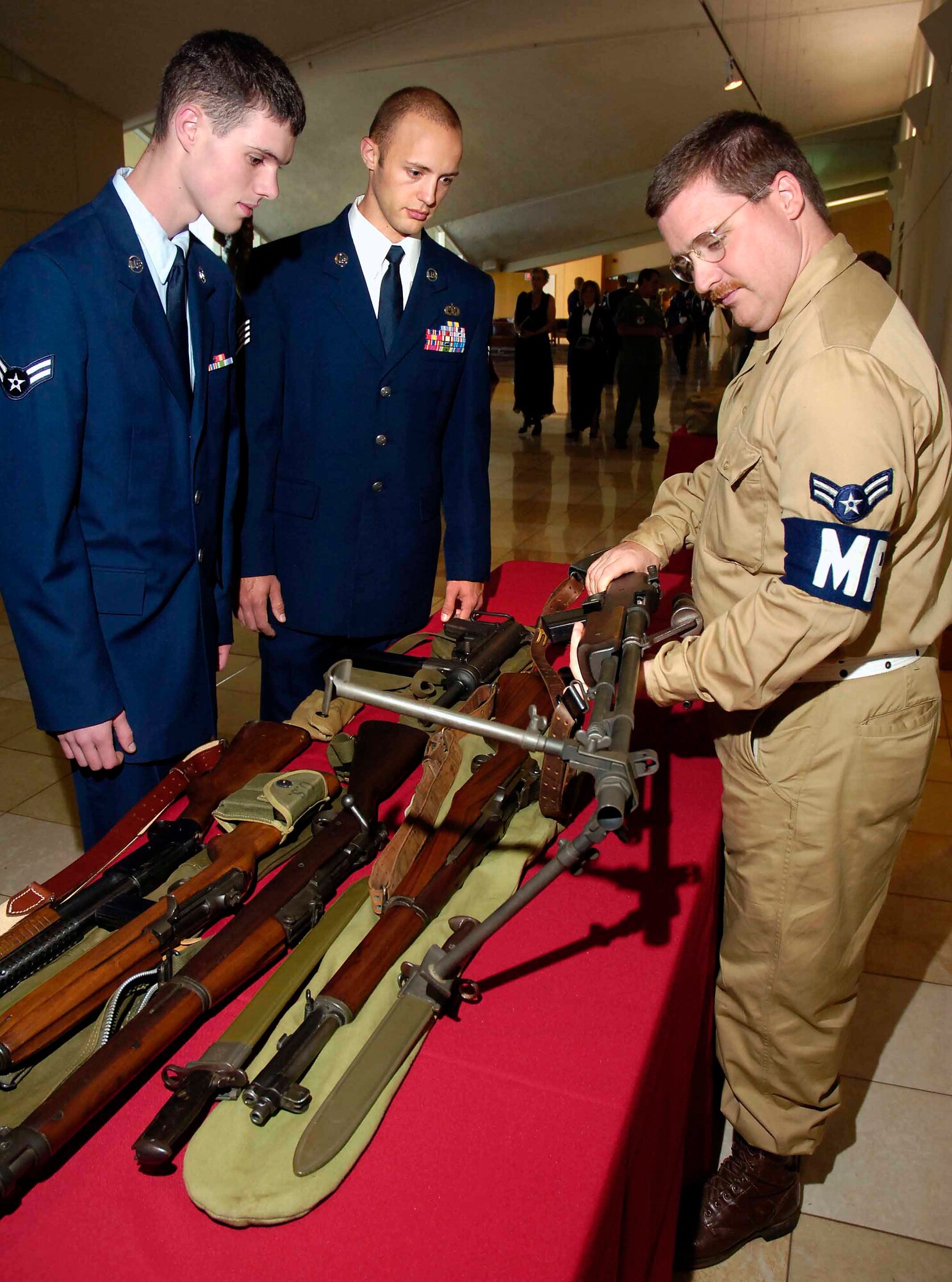 Airman 1st Class Thomas Aderman, 552nd Aircraft Maintenance Squadron, and Staff Sgt. Christopher Tolley, 507th Air Refueling Wing, view World War II and Korean War weapons displayed by a volunteer from the 45th Infantry Division Museum. (Air Force photo by Dave Faytinger)