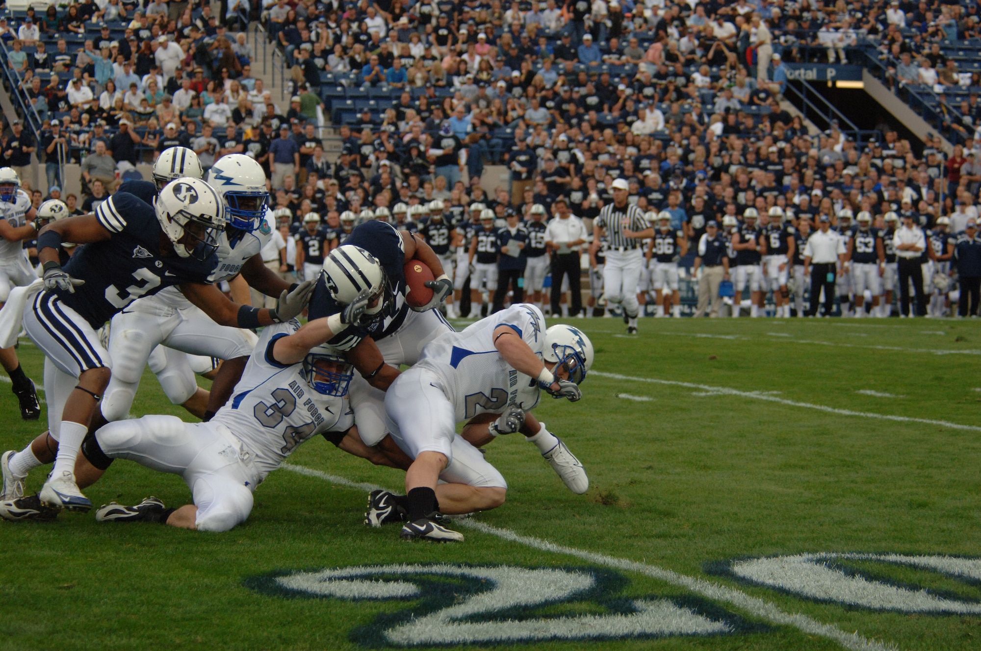 Air Force safety Chris Thomas, 34, and cornerback Carson Bird, 2, double team Brigham Young running back Masese Tonga, Sept. 22 in Provo, Utah. Tonga rushed 14 times for 41 yards and two touchdowns in BYU's 31-6 win. (U.S. Air Force photo/John Van Winkle) 
