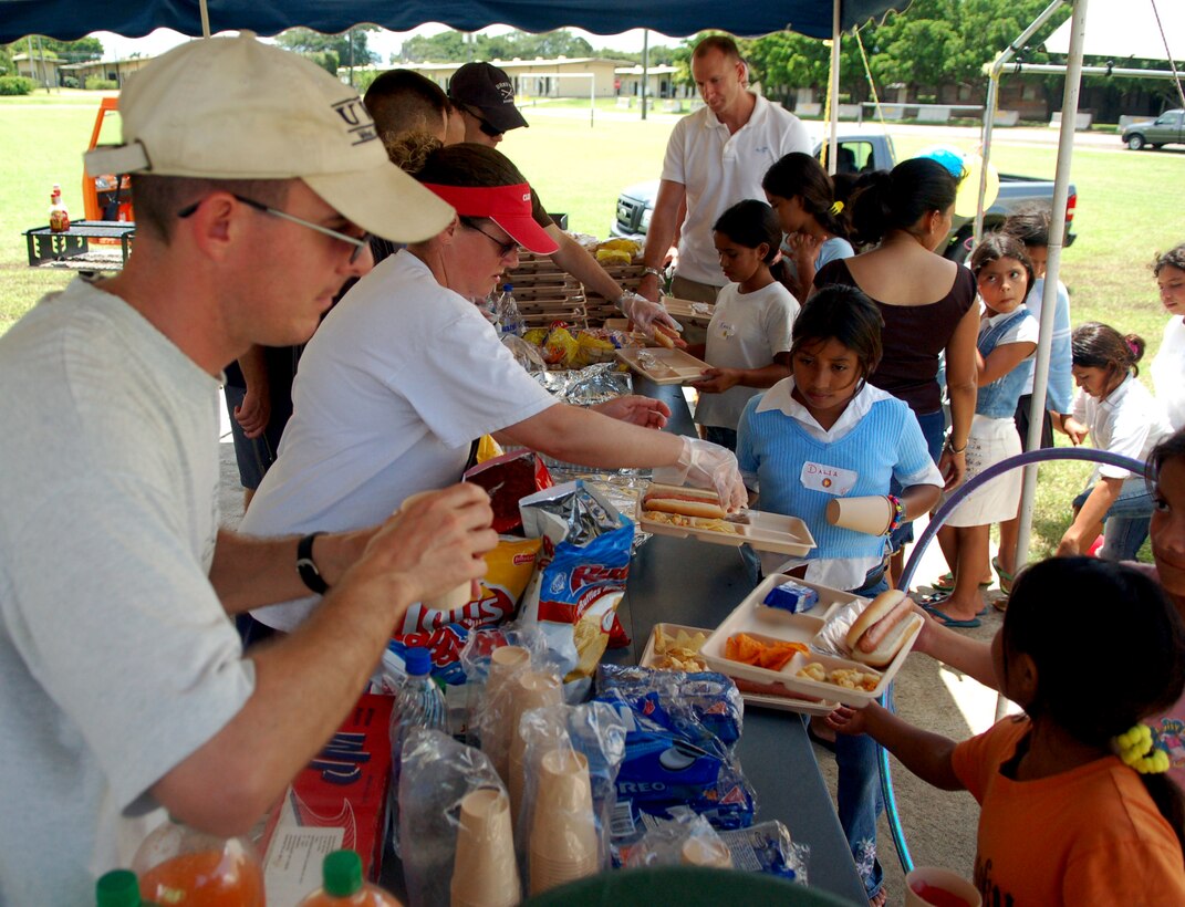 SOTO CANO AIR BASE, Honduras – Members of the United States Air Force cheerfully serve a hotdog lunch to Honduran children during a break in various games and activities.  Approximately 90 children from Nuestra Señora de Guadalupe Children's Home in Comayagua came out to enjoy the Annual Kids Day celebration September 22.  (U.S. Air Force photo by Staff Sgt. Austin M. May)