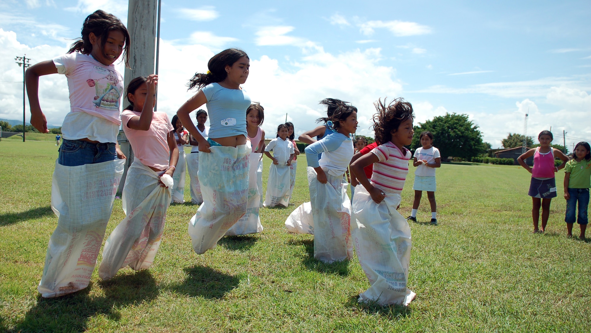 SOTO CANO AIR BASE, Honduras – As their friends enthusiastically cheer them on, a group of young Honduran girls race against each other in potato sacks.  Approximately 90 children from Nuestra Señora de Guadalupe Children's Home in Comayagua came out to enjoy the Annual Kids Day celebration September 22.  (U.S. Air Force photo by Staff Sgt. Austin M. May)