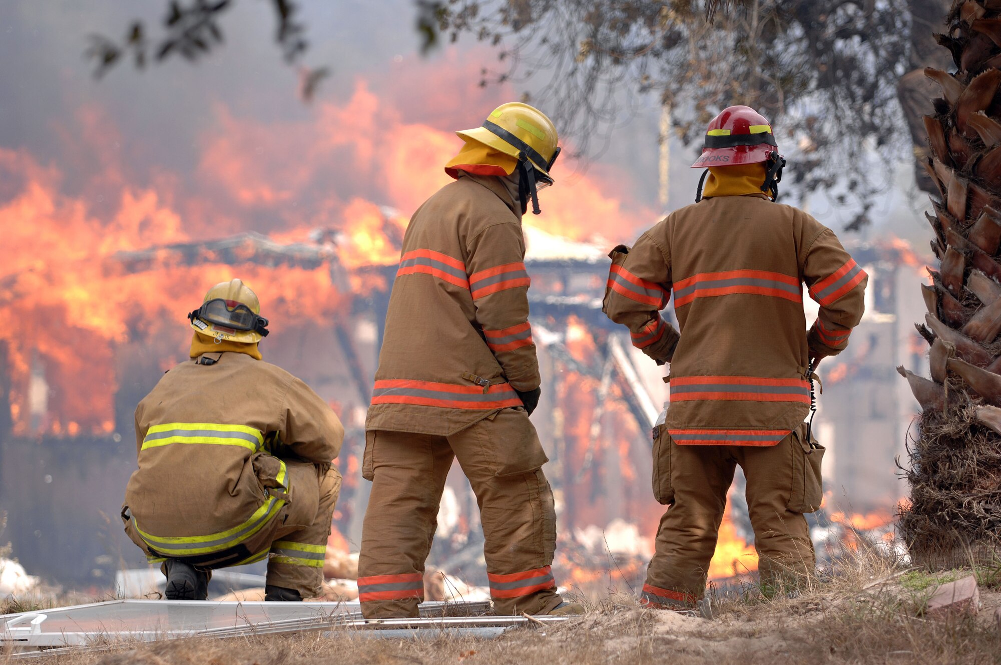 Three Vandenberg fire fighters analyze a burning house inside east housing on Sept. 21 in east base housing here. The 30th Civil Engineer Squadron Fire Protection Flight have five live training fires planned from 8:30 a.m. to 8 p.m. between Sept. 14 and Oct. 1. The training will consist of live fire training inside a residential structure and will give the firefighters the opportunity to get first-hand knowledge of fire behavior as well as the specific stages of fire growth in safer, controlled environment. (U.S. Air Force photo by Staff Sgt. Vanessa Valentine)