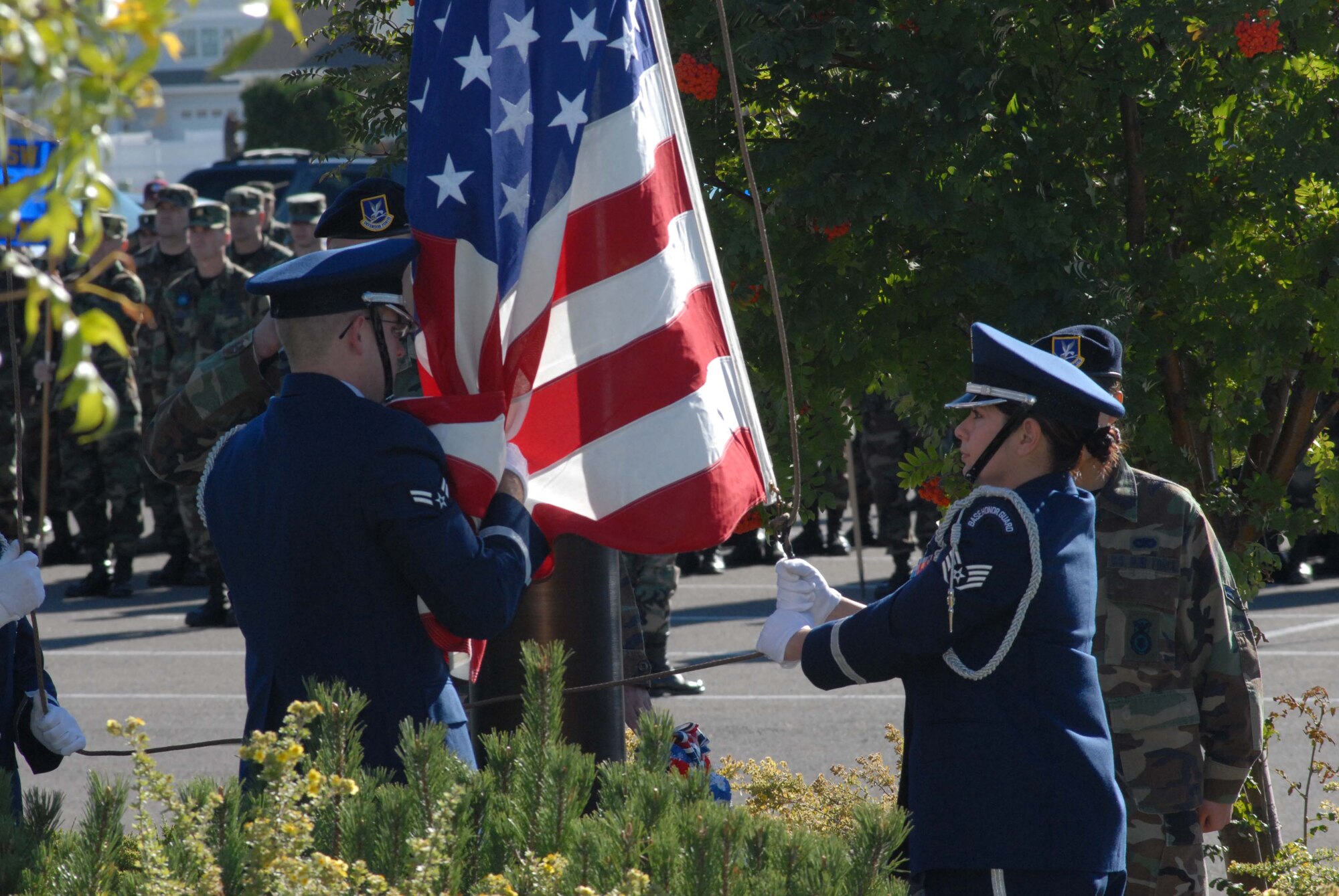 Airman 1st Class Jared Bobic gathers up the American flag being lowered by Staff Sgt. Vanessa LaBarge during the POW/MIA Remembrance Ceremony at Medal of Honor Park on Malmstrom Air Force Base Sept. 21. (U.S. Air Force photo/John Turner)