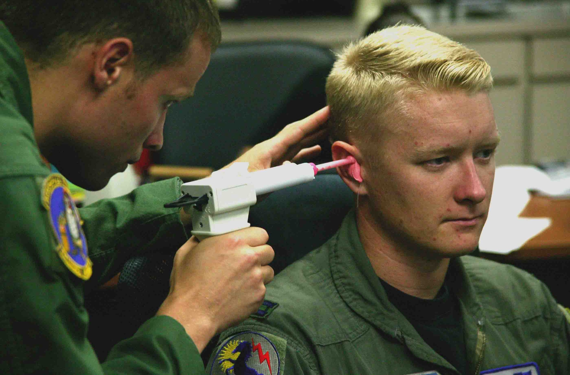 2nd Lt. Chris Reichlen (left) inserts silicone based mixture into the ear of Capt. Jerad Hand to make an inner-ear mold for the Attenuating Custom Communications Earpiece System Sept. 14 at Shaw Air Force Base, S.C. The ACCES device will significantly reduce surrounding ambient noise that pilots hear in the cockpit and increase the efficiency of radio communications. Lieutenant Reichlen is a 20th Aerospace Medicine Squadron aerospace physiologist, and Captain Hand is a 79th Fighter Squadron F-16 Fighting Falcon pilot. (U.S. Air Force photo/Senior Airman John Gordinier) 
