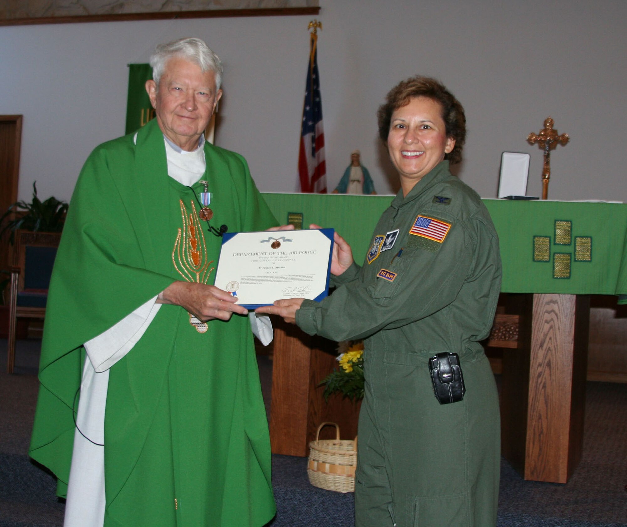 Rev. Francis McInnis, 341st Space Wing auxiliary Catholic chaplain, receives the Exemplary Civilian Service Award from Col. Sandra Finan, 341st SW commander, Sept. 23 at the Malmstrom Air Force Base, Mont., chapel. Father McInnis celebrates 50 years of ministry in the Air Force Chaplain Service, while 40 years were spent ministering at Malmstrom. (U.S. Air Force photo/Senior Airman Eydie Sakura).