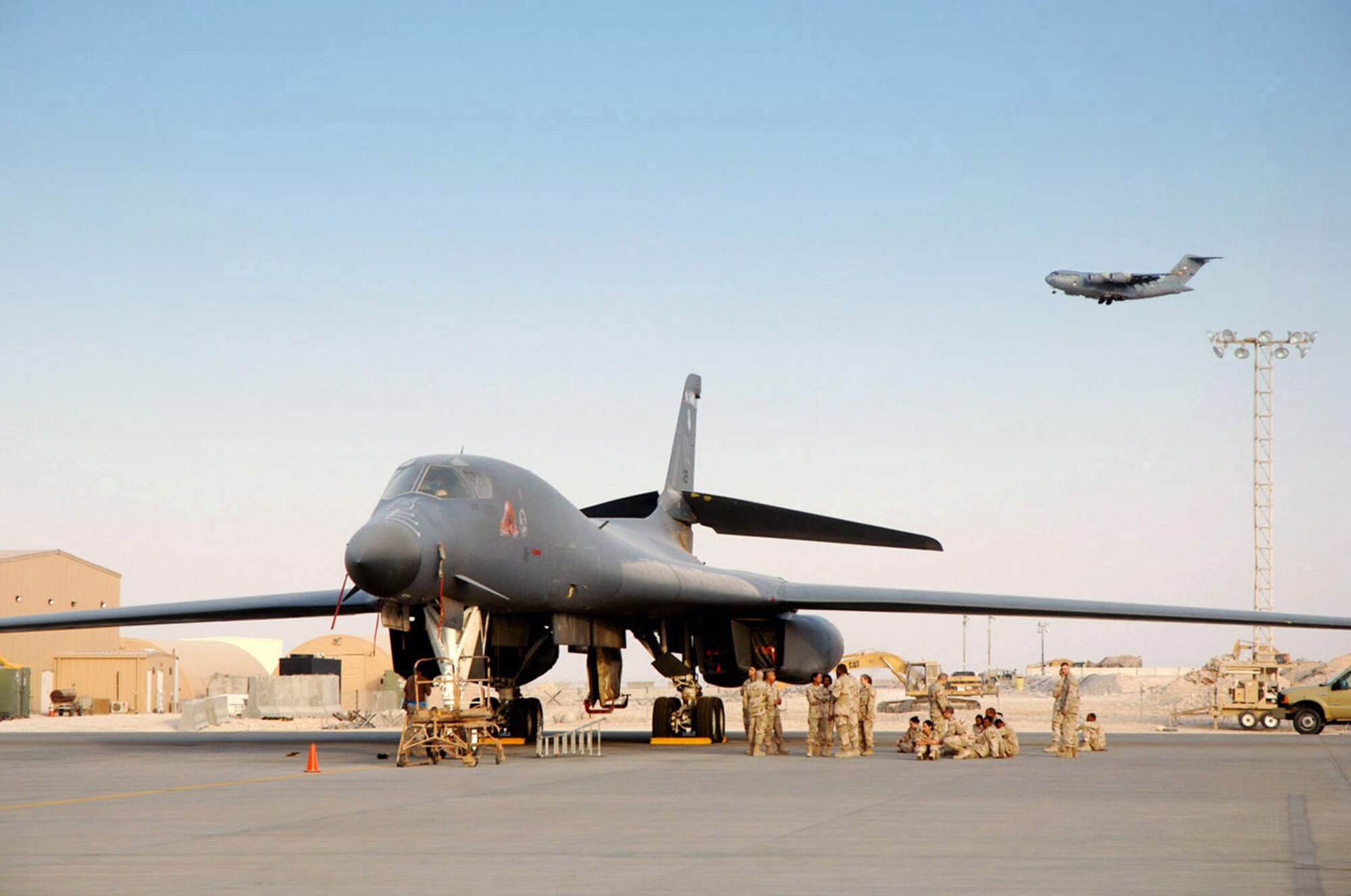 Maintainers ensure this B-1B Lancer is ready to go as a C-17 Globemaster III prepares to land at a forward deployed location in Southwest Asia.  (U.S. Air Force photo/Master Sgt. Ken Stephens)
