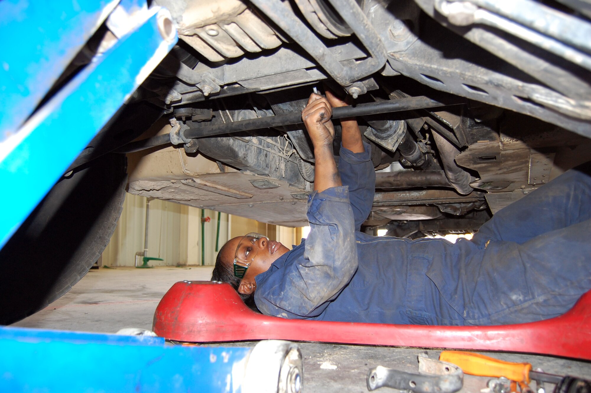 Senior Airman Monique Barnes, 386th Expeditionary Logistics Readiness, vehicle maintenance technician, tightens a u-bolt on a drive axel of a hummev Sept. 24 in the transportation garage. SrA. Barnes rides a shop car making it easier for her to move around under the vehicle. (Photo by Staff Sgt. Phillip Butterfield)