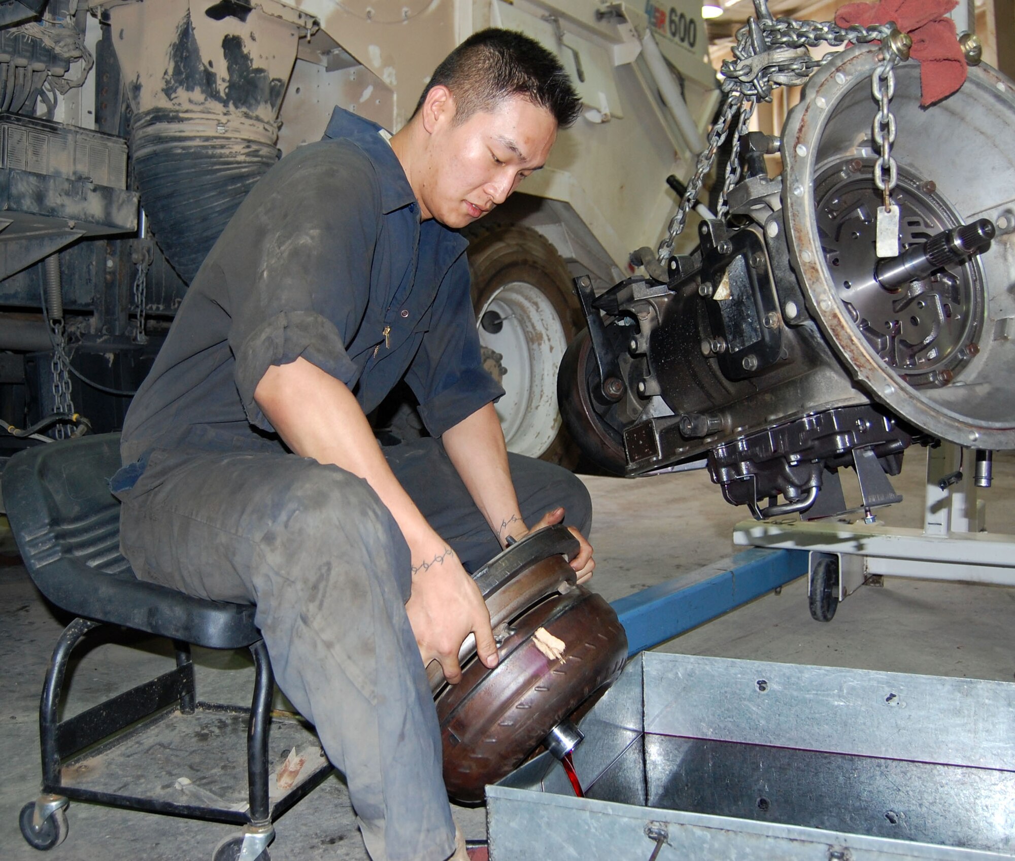Senior Airman Dylan Johnston, 386th Expeditionary Logistics Readiness, vehicle maintenance technician, pours out fluid from a transmission torque converter into a collection pan Sept. 24 in the transportation garage. The torque converter was removed to inspect the transmission for other problems. (Photo by Staff Sgt. Phillip Butterfield)