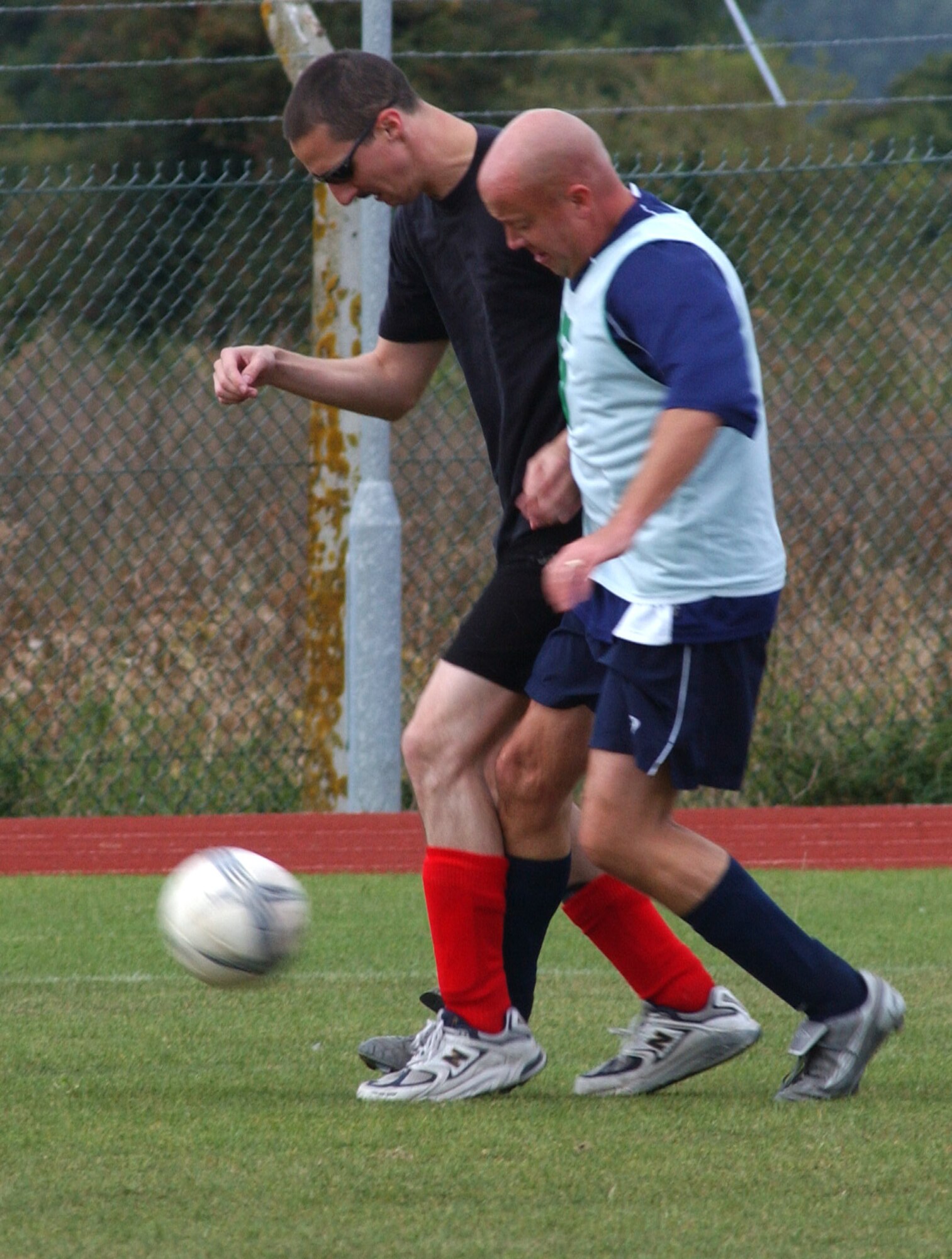 Chris Greer (black shirt), from the 100th Logistics Readiness Squadron, tangles with Eric Evers, 95th Reconnaissance Squadron, during the outdoor intramural soccer at RAF Mildenhall, Sept. 19.