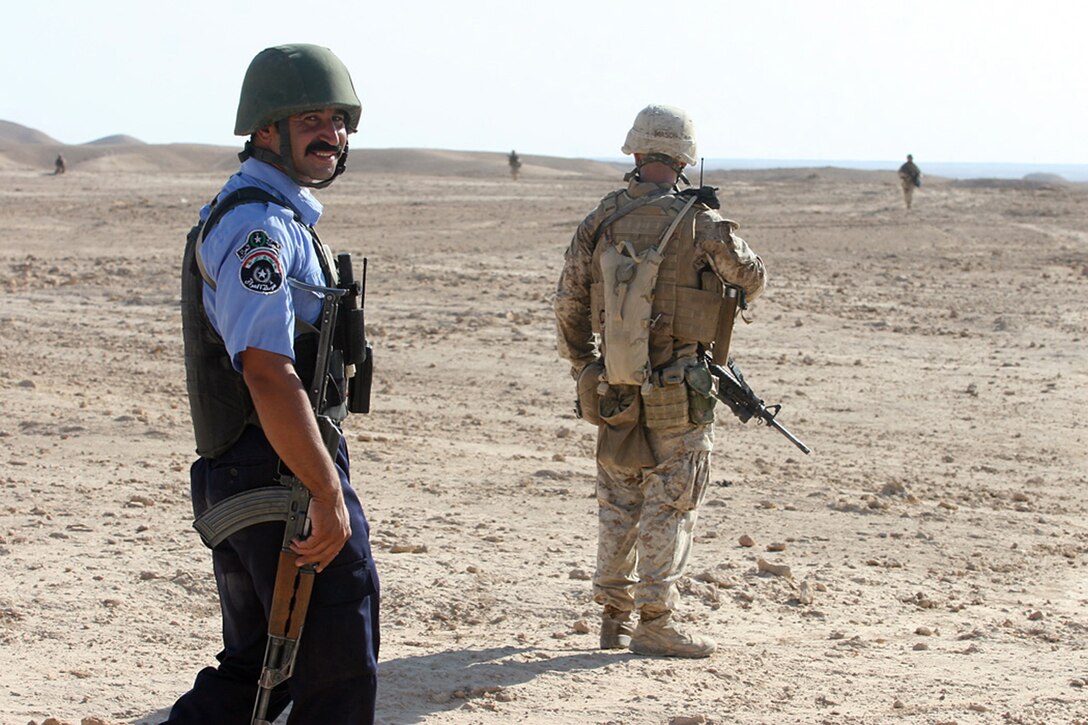 EXPEDITIONARY PATROL BASE - DULAB, Iraq, (Sept. 26, 2007) – An Iraqi policeman smiles while Lance Cpl. Patrick K. Mason (center), a squad leader with Company A, 1st Battalion, 7th Marine Regiment, Regimental Combat Team 2, directs the members of his squad on a patrol during Operation Bell Hurriyah. Bell Hurriyah, which means Enjoy Freedom, is battalion-wide operation directed at stopping the increase of insurgent activity during the Muslim holy month of Ramadan. Official Marine Corps Photo By Cpl. Ryan C. Heiser.