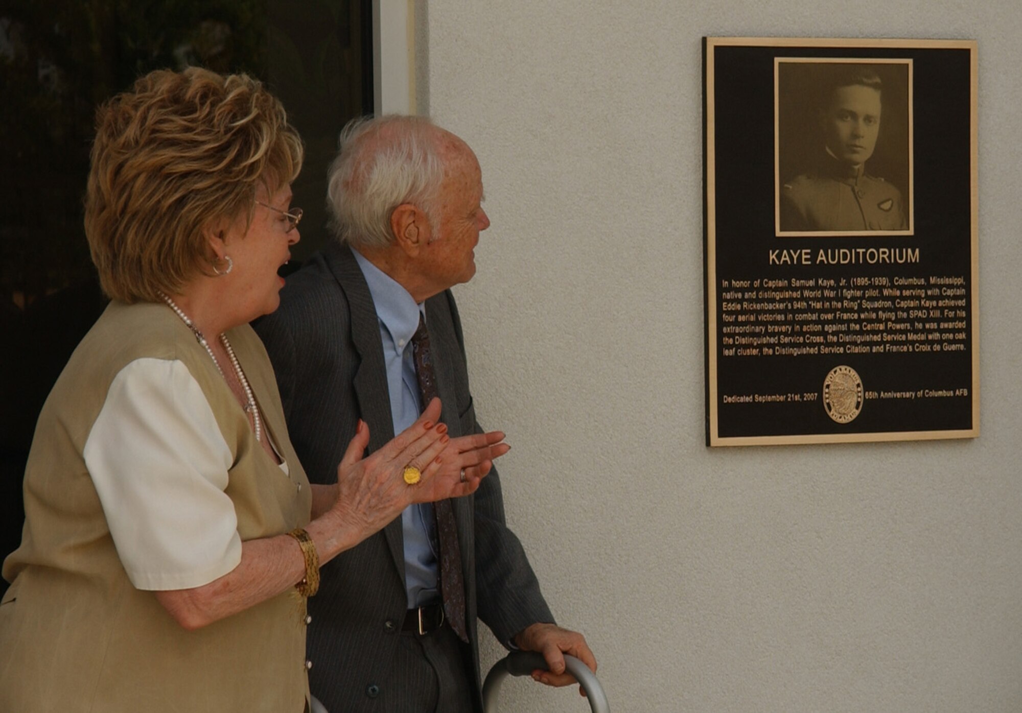 Lorraine Tucker and Dr. John "Jack" Kaye, children of Capt. Sam Kaye, witness the unveiling of the plaque that hangs outside the Kaye Auditorium. The auditorium was named in honor of their father Friday in a ceremony at the auditorium. (U.S. Air Force photo)
