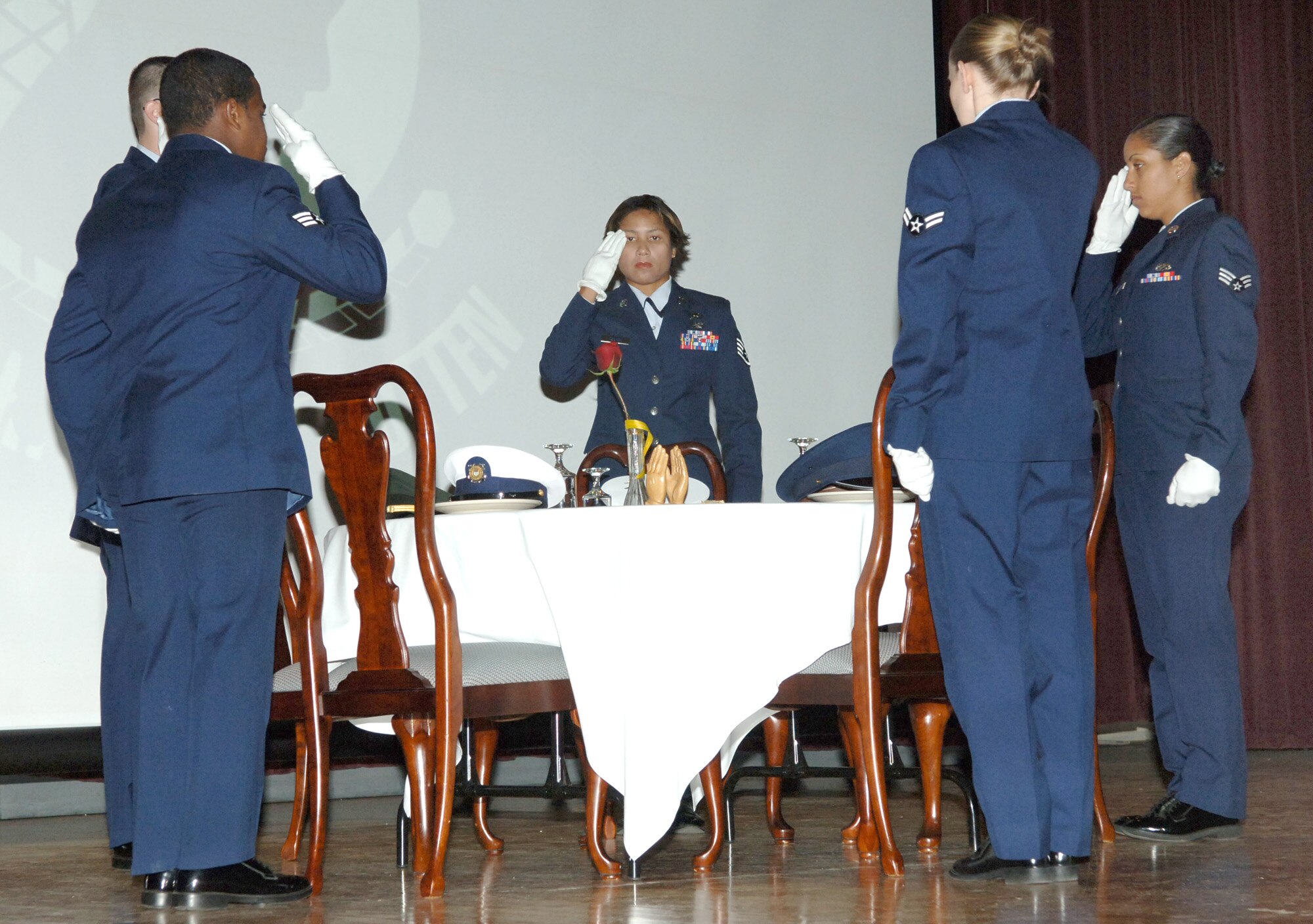 FAIRCHILD AIR FORCE BASE, Wash. – The Fairchild Honor Guard salutes prisoners of war and missing-in-action personnel during the POW/MIA ceremony held at the theater here Sept. 14. The five empty settings at the missing-comrade table represent servicemembers from the Army, Navy, Marine Corps, Air Force and Coast Guard. (U.S. Air Force photo/Airman 1st Class Jocelyn Ford)
