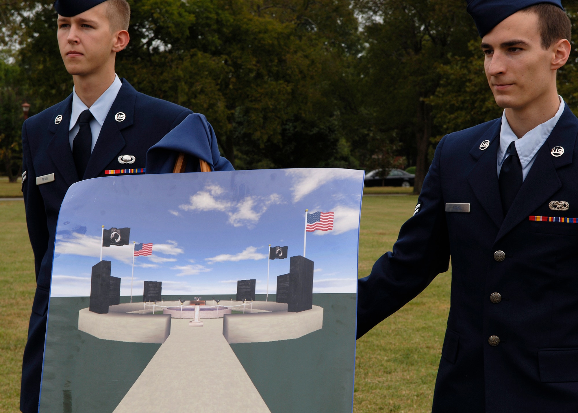 Airmen 1st Class Rodney Spain, 36th Intelligence Squadron, and Maximilian Zanol, 1st Equipment Maintenance Squadron, unveil the winning design of the future POW/MIA memorial Sept. 21 during the POW/MIA ceremony. The memorial will be built in Memorial Park. (U.S. Air Force photo/Senior Airman Dawn Duman)