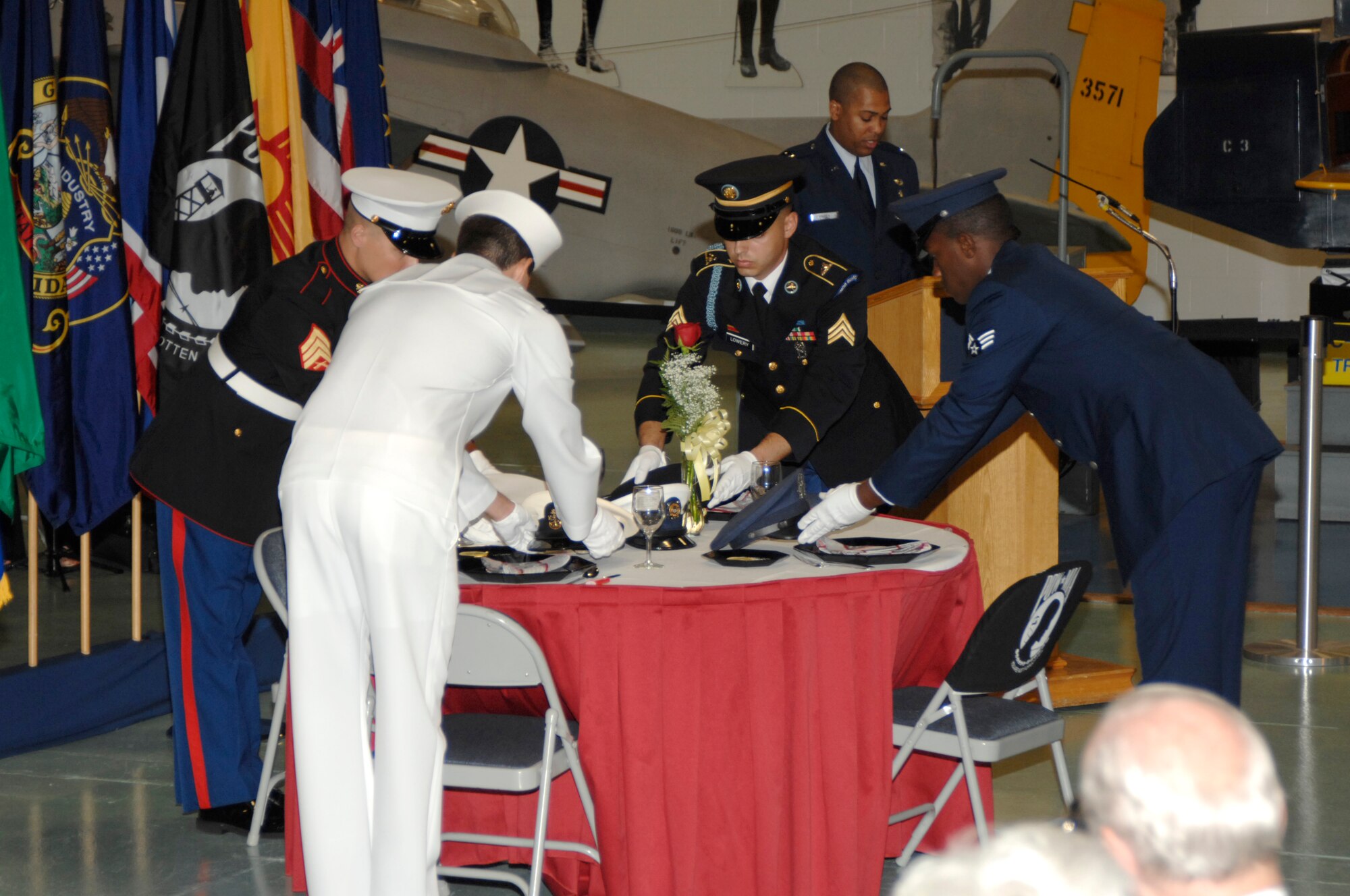 EGLIN AIR FORCE BASE, Fla. -- An Airman, a Soldier, a Sailor and a Marine from the Navy School Explosive Ordnance Disposal saves a ceremonial seat for armed forces members who are still missing in action during the Prisoner of War Missing in Action Recognition Day ceremony Sept. 21 at the Air Force Armament Museum. The tradition of setting the table is to symbolize "you are not forgotten." (U.S. Air Force photo by Mike Fleck)