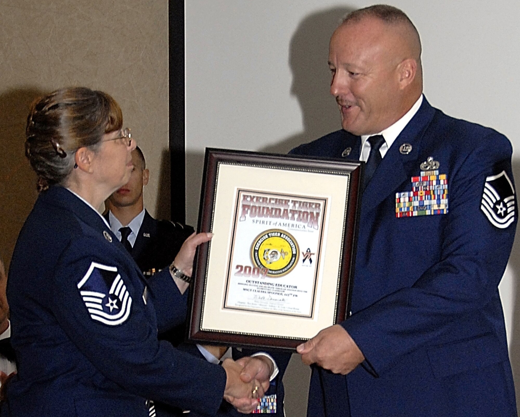 Master Sgt. Claudia Spooner, (left) Hardin, Mo., resident and U.S. Air Force reservist, accepts the Spirit of America award from the National Exercise Tiger Association's Missouri associate state director Master Sgt. Bob Jackson, at the association's annual awards banquet in Columbia, Mo., Sept. 21.
Sergeant Spooner received the award in recognition for being the "Outstanding Missouri Educator in Aviation" for her work with the Wright Flight program at Hardin Central and Norborne schools. Wright Flight is a youth-mentoring program, which uses aviation notables such as the Wright brothers and World War II's Tuskegee Airmen as examples to help children set and achieve goals.
The National Exercise Tiger Association, which recognizes military members for excellence in service, is a national commemorative foundation formed to keep alive the memory of those American servicemen killed aboard three ships attacked by German torpedo boats during a World War II exercise April 28, 1944. At the time of the attack, with 749 killed, it was the single largest loss of American military lives since the Japanese attack on Pearl Harbor. (US Air Force photo/Master Sgt. Bill Huntington)