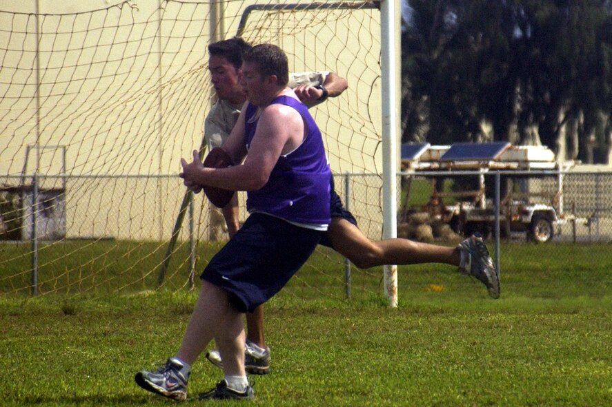 A 506th Air National Guard player strives to hold on to his catch as a player from the Special Operations Command, Pacific team tries for an interception.          