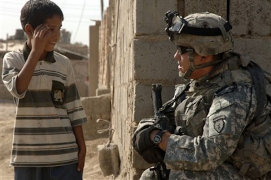A U.S. Army soldier talks to an Iraqi child while conducting a patrol in Haswra, Iraq, on Sept. 20, 2007.  