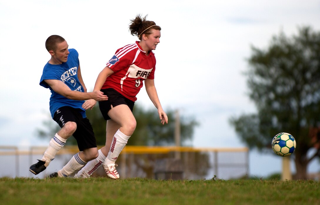 Senior Airman Brian Kimball, 36th Communications Squadron, and Lindy, wife of Matthew Derheim from the 36th Civil Engineering Squadron, run towards the ball during their intramural soccer game, Sept. 25.  The 36th CES won the game against the 36th CS with a resulting score of 8-1.  (U.S. Air Force photo/Senior Airman Miranda Moorer)                                   