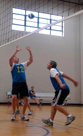 Eric Sifers, 437th Civil Engineer Squadron, sets a spike for his teammate, Russell Patterson, during a game of volleyball against the 437th Communications Squadron at the Fitness and Sports Center Tuesday. (U.S. Air Force photo/Airman 1st Class Cynthia Spalding)