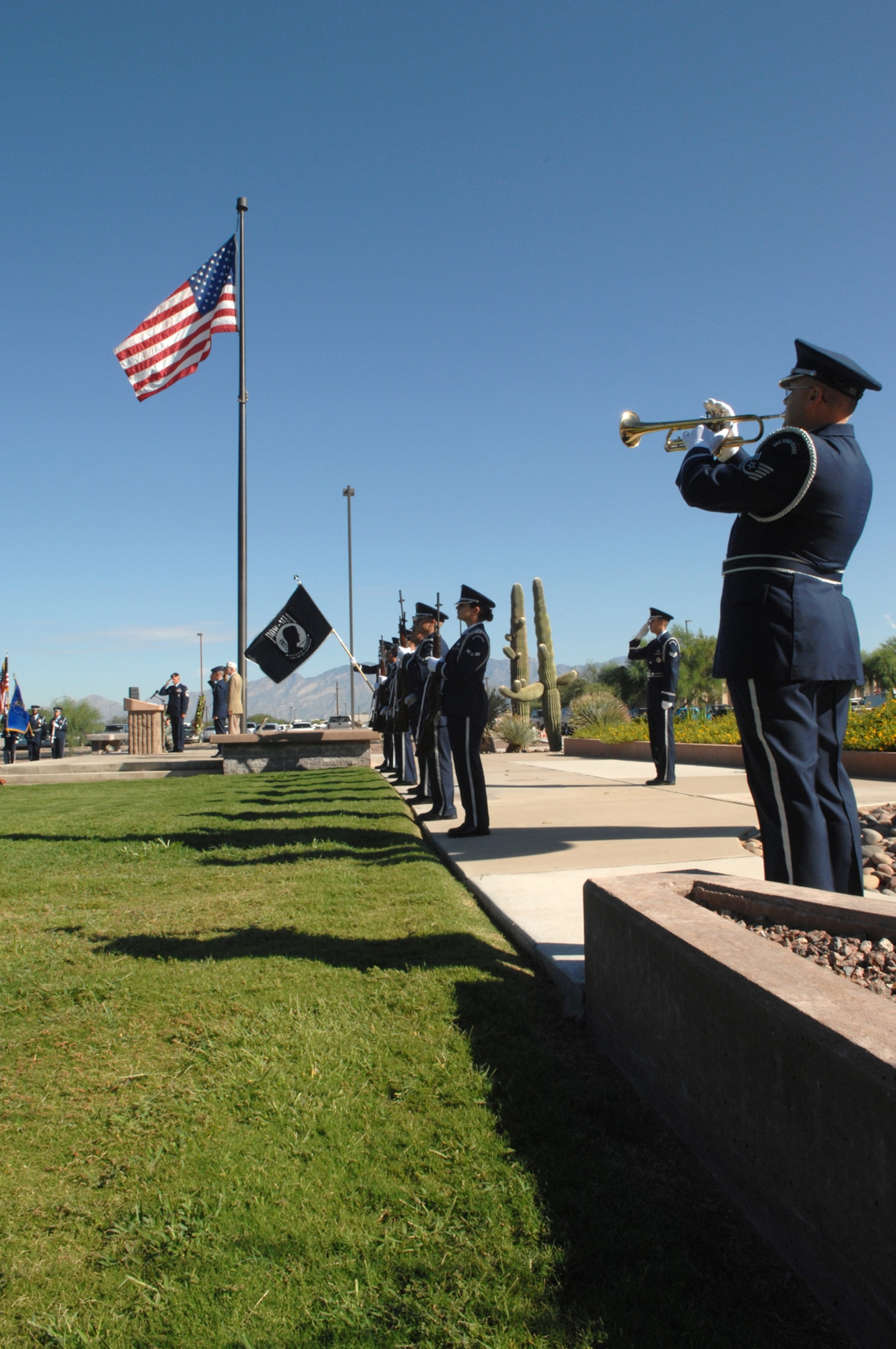 The Davis-Monthan Air Force Base Honor Guard presents arms as Technical Sgt. William Macek plays Taps during the Prisoner of War/Missing in Action ceremony held on Sept. 21 at Davis-Monthan Air Force Base, Ariz.  The ceremony was held as part of the National POW/MIA Recognition Day.  (U.S. Air Force photo by A1C Alesia Goosic)