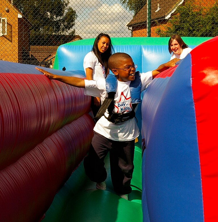 Jakim Brown, 8, tries to grab the beanbag on the inflatable bungee run Saturday, at the Day for Kids at the RAF Mildenhall Youth Center.  Georgia Lau and Georgie Hallet were on hand to help children with the harnesses. (U.S. Air Force photo by Karen Abeyasekere)
