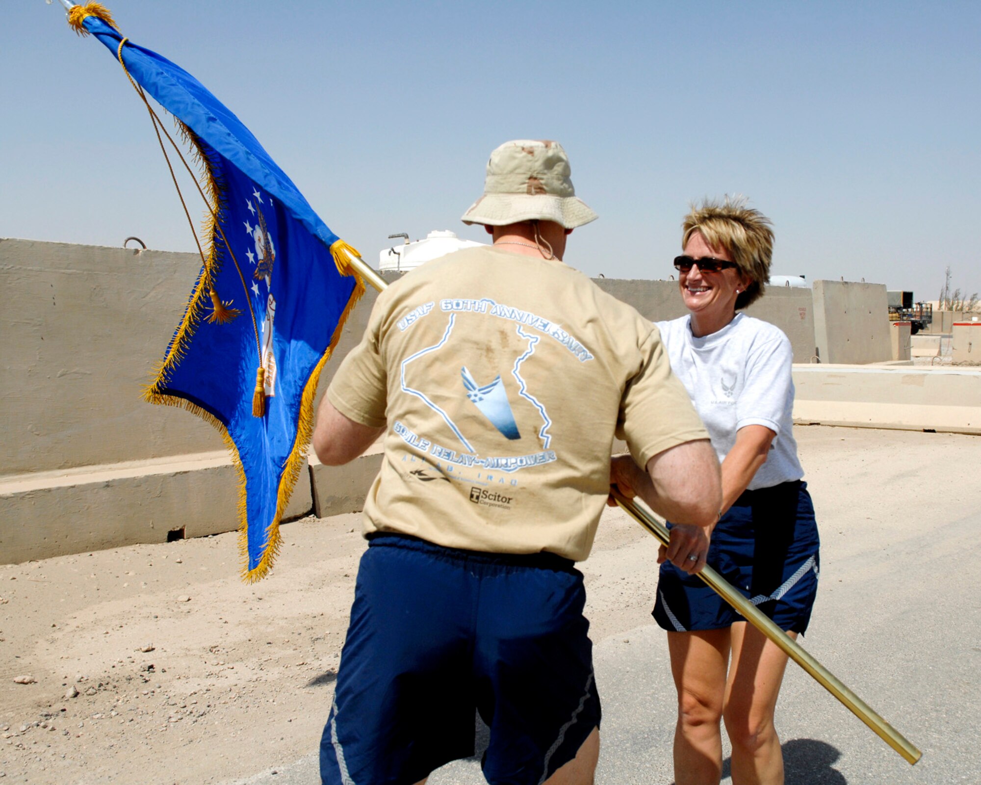 Master Sgt. Mary Lewis, Air Expeditionary Group, passes the flag to Capt Mathew Parker, Expeditionary Service Squadron, during a 60 mile Air Force flag relay at Ali Air Base, Iraq, Sept. 18.  Each participant in the event carried a flag for one mile of the relay, which was held to celebrate the Air Forces 60th birthday.      

U.S. Air Force Photo by Master Sgt. Robert Valenca (Released)   